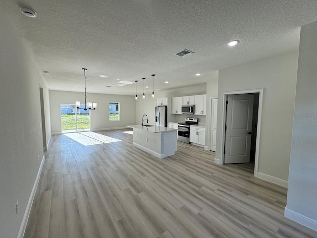 kitchen with visible vents, a sink, open floor plan, stainless steel appliances, and white cabinets