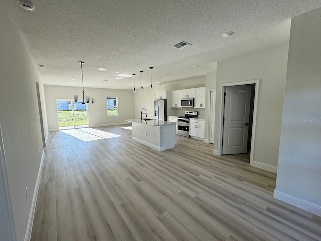 kitchen featuring open floor plan, light wood-type flooring, appliances with stainless steel finishes, white cabinetry, and a kitchen island with sink