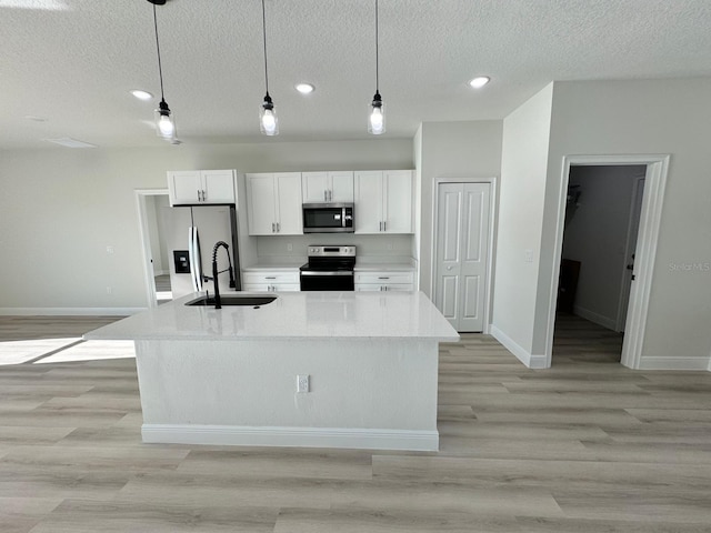 kitchen featuring a center island with sink, appliances with stainless steel finishes, light wood-style floors, white cabinetry, and a sink