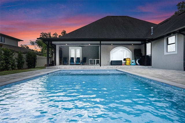 pool at dusk featuring a patio and french doors