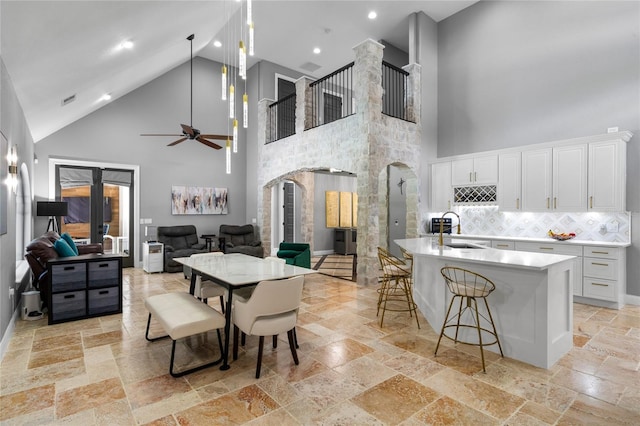 dining room with ceiling fan, sink, and high vaulted ceiling