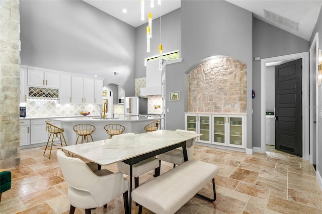 dining space with high vaulted ceiling and sink