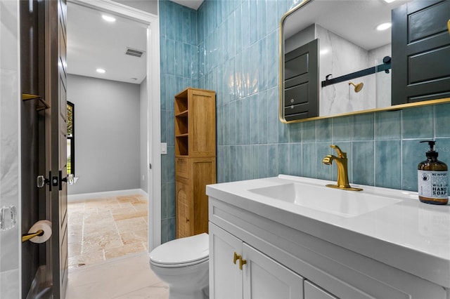 bathroom featuring vanity, toilet, and tile walls