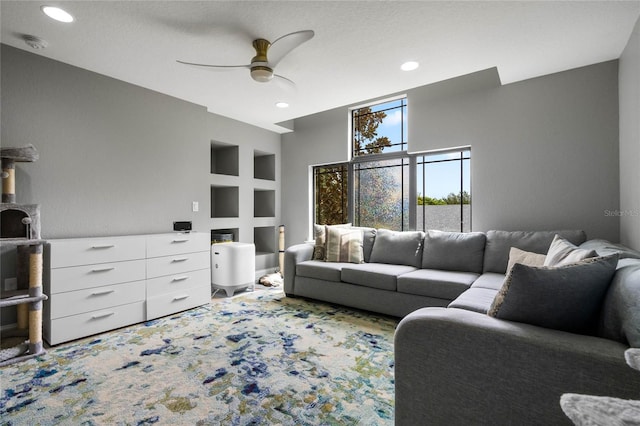 living room with built in shelves, ceiling fan, and a textured ceiling