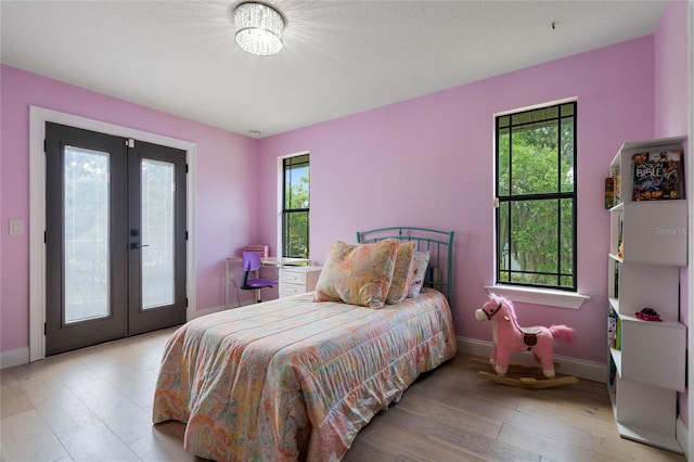 bedroom with access to exterior, light wood-type flooring, and french doors