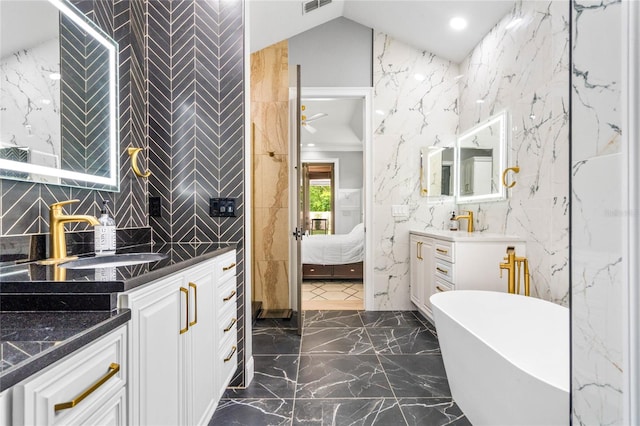 bathroom featuring a tub to relax in, vanity, and vaulted ceiling