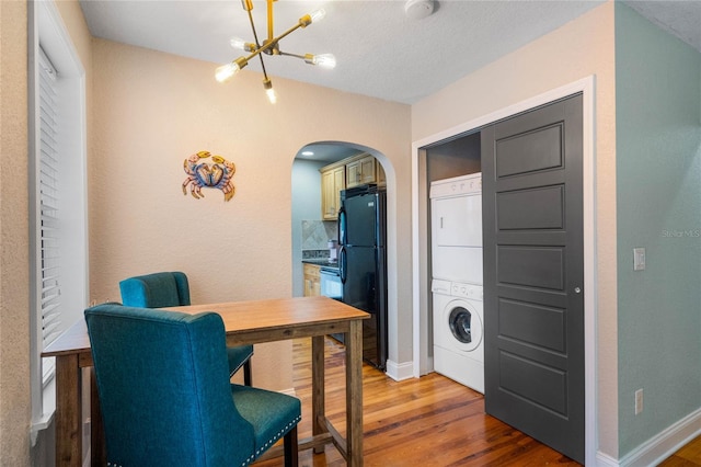 home office featuring wood-type flooring, a textured ceiling, and stacked washer / dryer