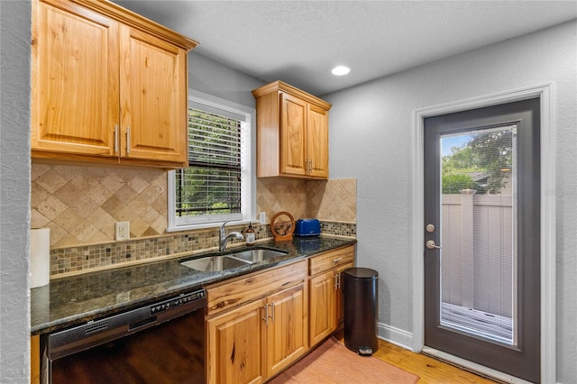 kitchen with plenty of natural light, dishwasher, sink, and dark stone counters