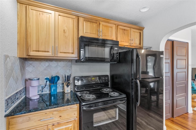 kitchen with dark stone countertops, light hardwood / wood-style flooring, black appliances, decorative backsplash, and a textured ceiling