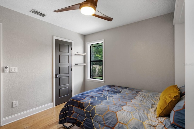 bedroom featuring ceiling fan, hardwood / wood-style flooring, and a textured ceiling