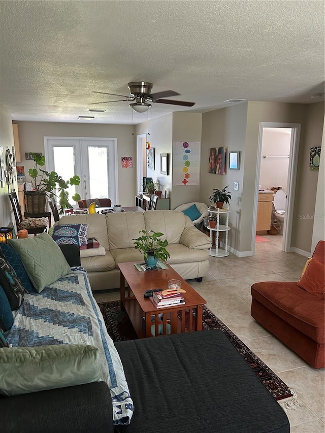 tiled living room with ceiling fan, a textured ceiling, and french doors