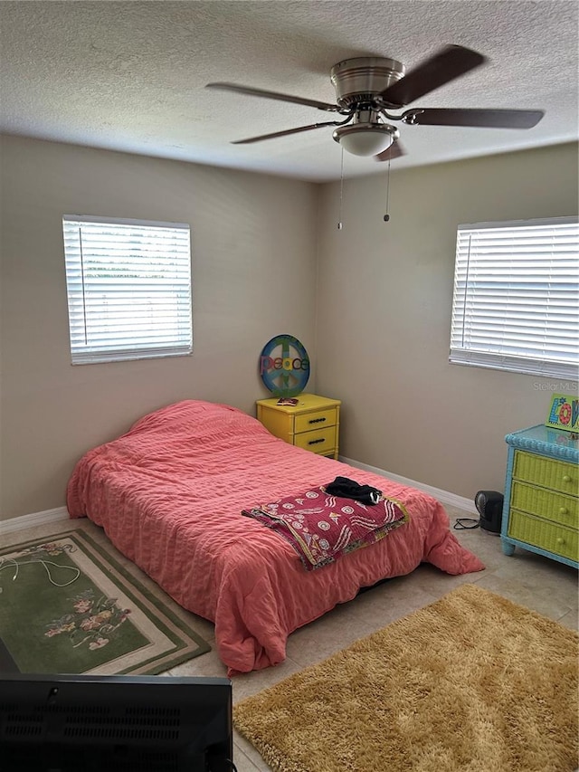 bedroom with a textured ceiling, ceiling fan, and light tile patterned flooring