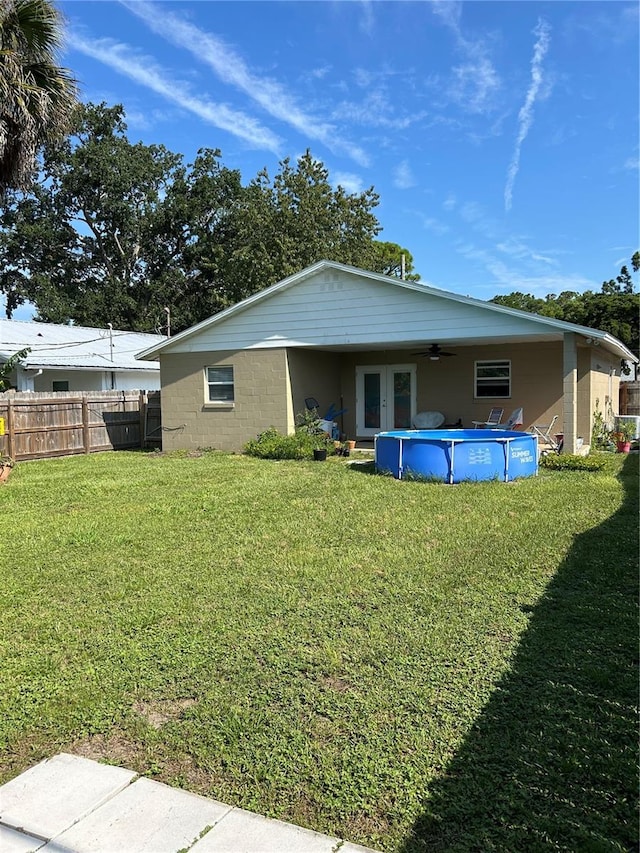 rear view of house featuring a fenced in pool, french doors, and a yard