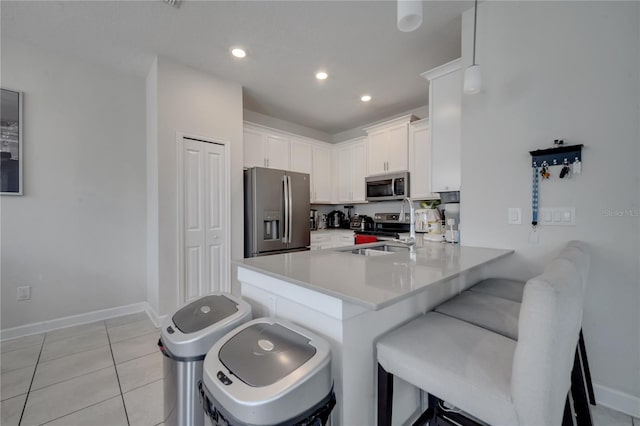 kitchen featuring a kitchen breakfast bar, light tile patterned floors, appliances with stainless steel finishes, kitchen peninsula, and sink