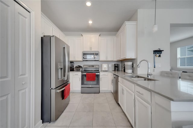 kitchen with pendant lighting, stainless steel appliances, kitchen peninsula, sink, and white cabinets