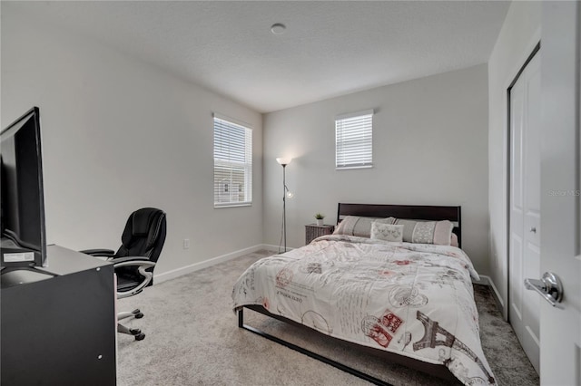 bedroom with a textured ceiling, light colored carpet, and a closet