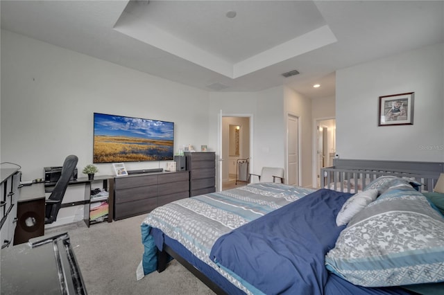 carpeted bedroom with a closet and a raised ceiling