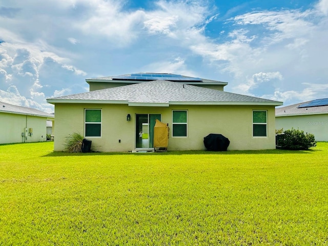 rear view of house with a yard and solar panels