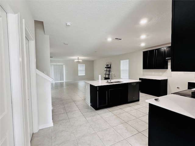 kitchen featuring a textured ceiling, a center island with sink, black dishwasher, light tile patterned floors, and sink