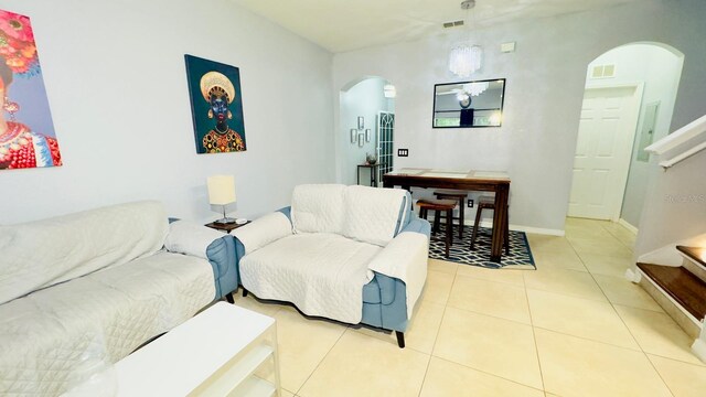 living area featuring arched walkways, visible vents, stairway, and light tile patterned floors