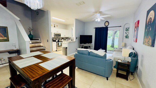 living area with visible vents, baseboards, stairway, light tile patterned flooring, and ceiling fan with notable chandelier