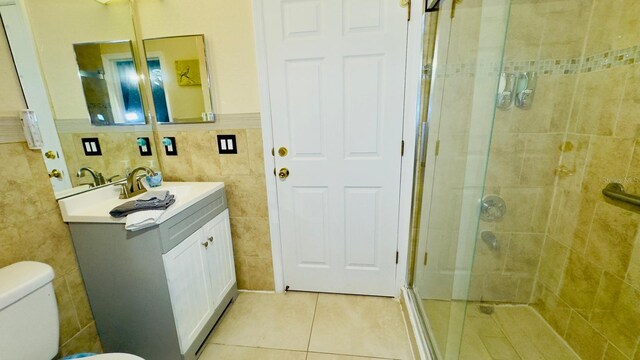 bathroom featuring tile patterned flooring, toilet, vanity, tile walls, and a shower stall