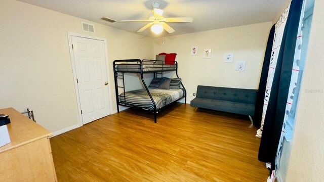 bedroom with ceiling fan, wood finished floors, visible vents, and baseboards