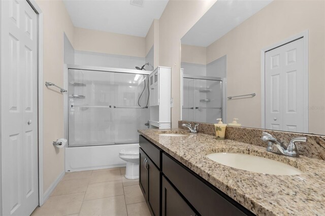 full bathroom featuring tile patterned floors, vanity, toilet, and combined bath / shower with glass door