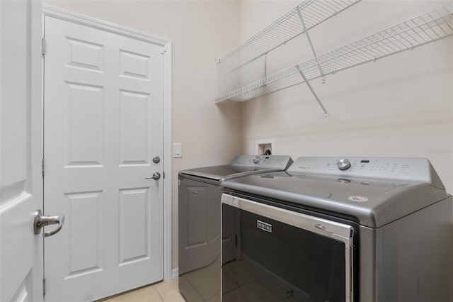 laundry area featuring separate washer and dryer and light tile patterned flooring