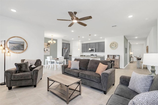 tiled living room with ceiling fan with notable chandelier