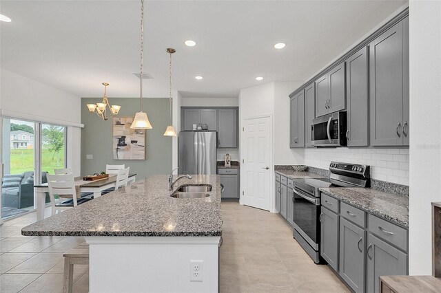 kitchen featuring appliances with stainless steel finishes, tasteful backsplash, sink, pendant lighting, and gray cabinets