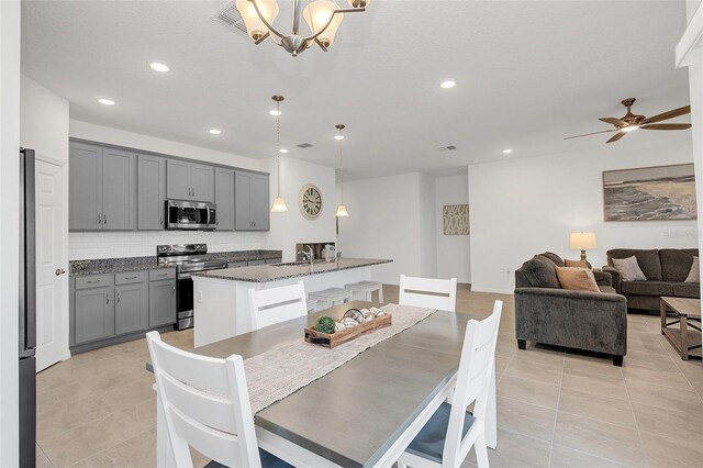 dining area with ceiling fan with notable chandelier, light tile patterned flooring, and sink