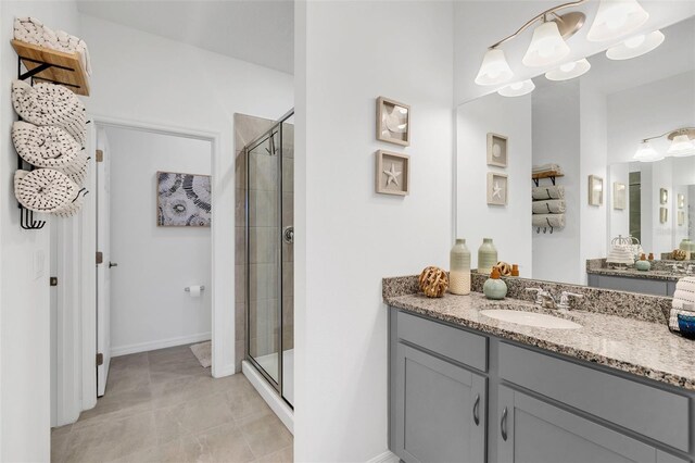 bathroom featuring a shower with door, vanity, and tile patterned flooring