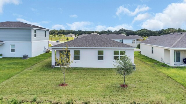 rear view of house featuring cooling unit and a lawn