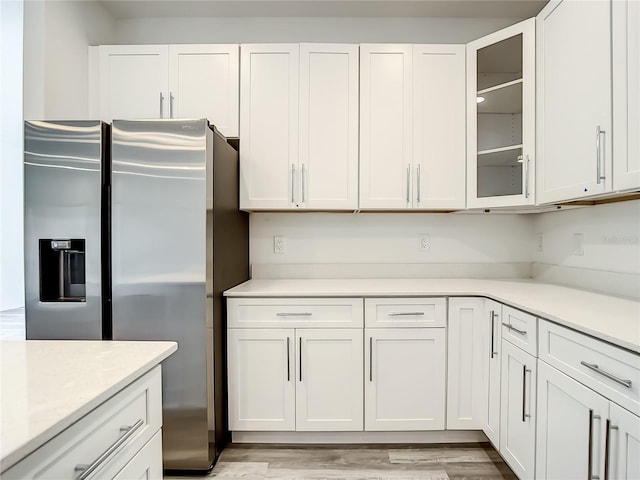 kitchen with white cabinets, stainless steel fridge with ice dispenser, and light wood-type flooring