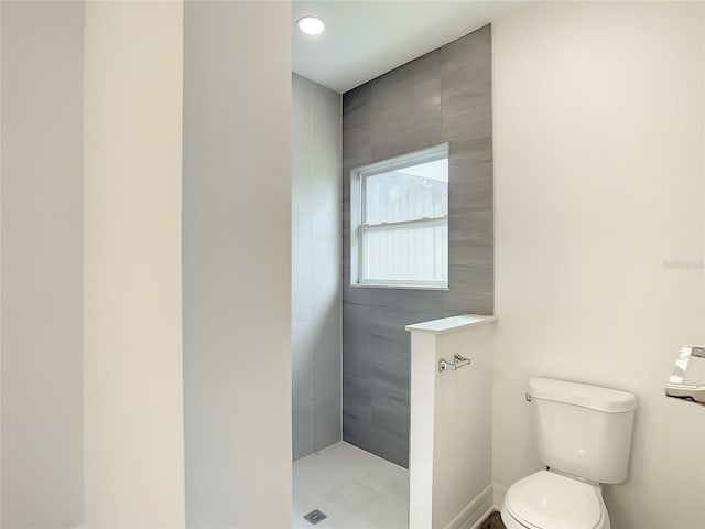 bathroom with tiled shower and toilet