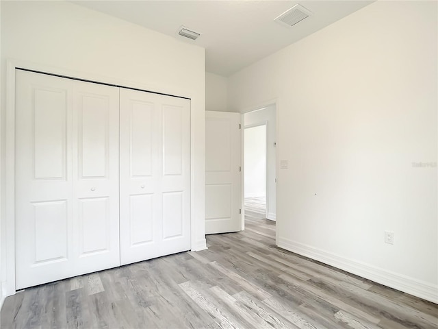 unfurnished bedroom featuring light hardwood / wood-style flooring and a closet