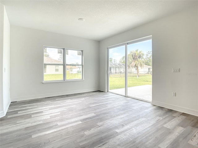 empty room with light hardwood / wood-style floors and a textured ceiling