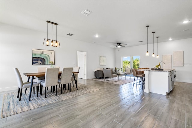 dining space with light hardwood / wood-style flooring, ceiling fan, and sink