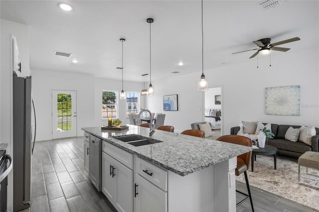 kitchen with sink, wood-type flooring, an island with sink, ceiling fan, and pendant lighting