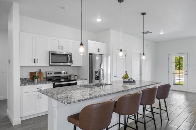 kitchen featuring appliances with stainless steel finishes, white cabinetry, sink, dark hardwood / wood-style floors, and a center island with sink