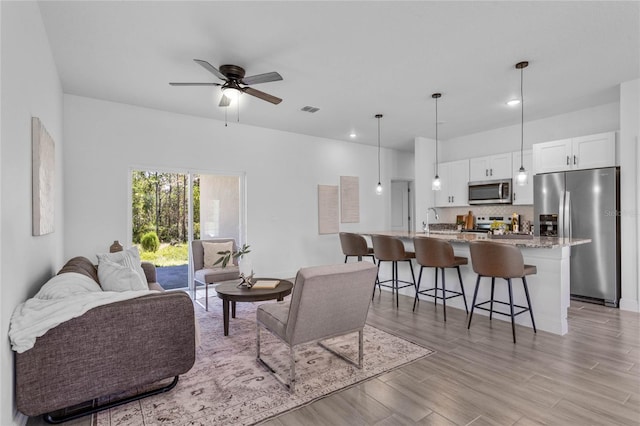 living room featuring ceiling fan, sink, and light hardwood / wood-style flooring