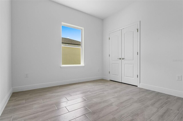 unfurnished bedroom featuring light hardwood / wood-style flooring and a closet