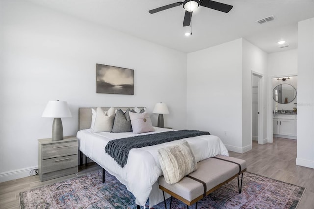 bedroom featuring sink, ceiling fan, light hardwood / wood-style floors, and ensuite bath