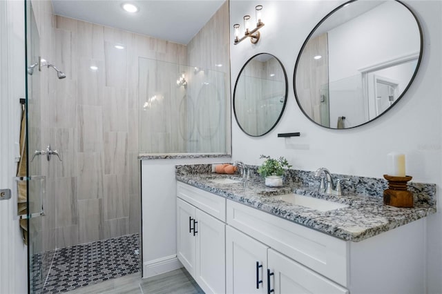 bathroom with tiled shower and vanity