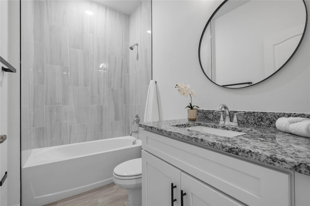 full bathroom with tiled shower / bath, toilet, hardwood / wood-style flooring, and vanity