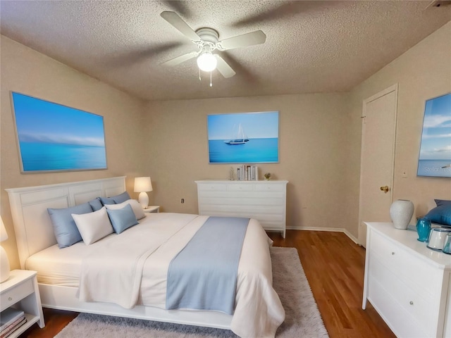 bedroom with a textured ceiling, hardwood / wood-style flooring, and ceiling fan