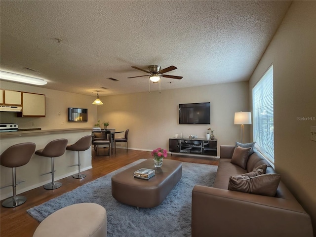 living room with a textured ceiling, ceiling fan, and hardwood / wood-style flooring