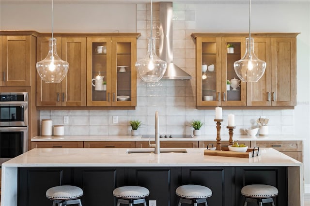 kitchen with pendant lighting, tasteful backsplash, light stone counters, double oven, and a breakfast bar area