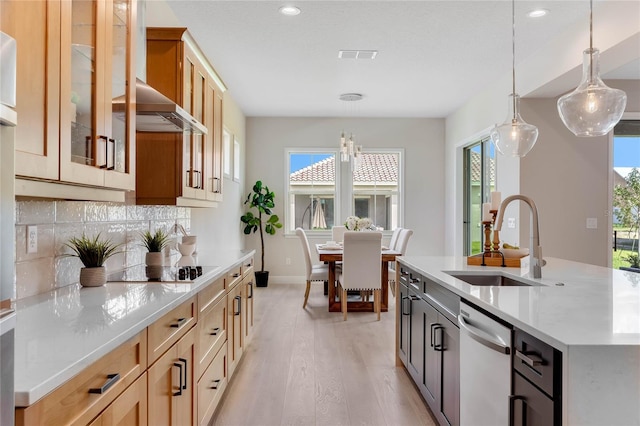 kitchen with wall chimney exhaust hood, a wealth of natural light, a center island with sink, and sink